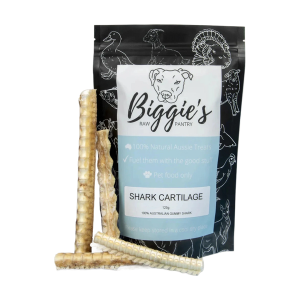 A bag of Biggies Shark Cartilage treats is displayed against a neutral background. The package features a playful design with illustrations of various animals and highlights that the product is 100% natural and sourced from Australian.